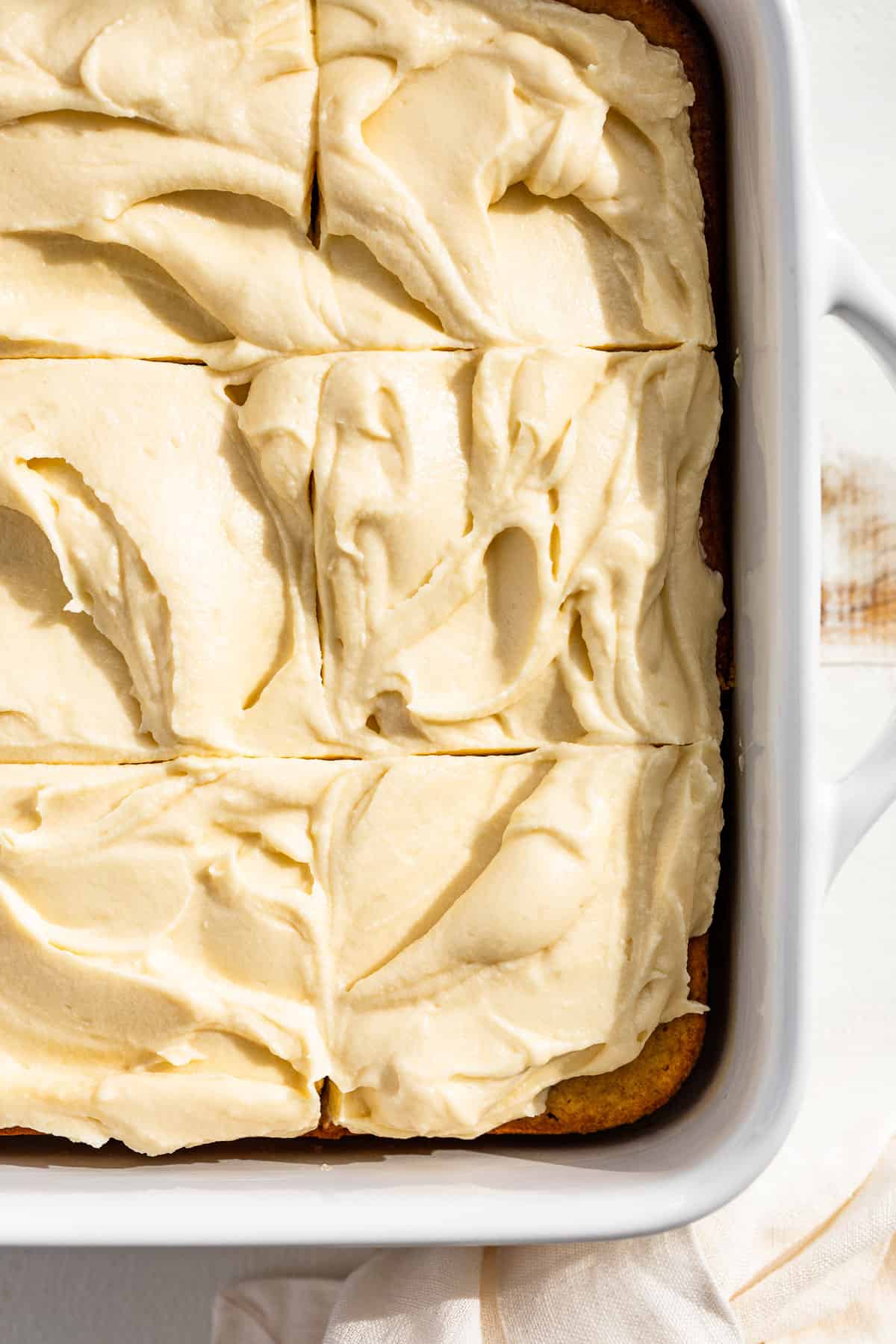 Straight down view of gluten free banana cake frosted with cream cheese frosting and cut into square slices.