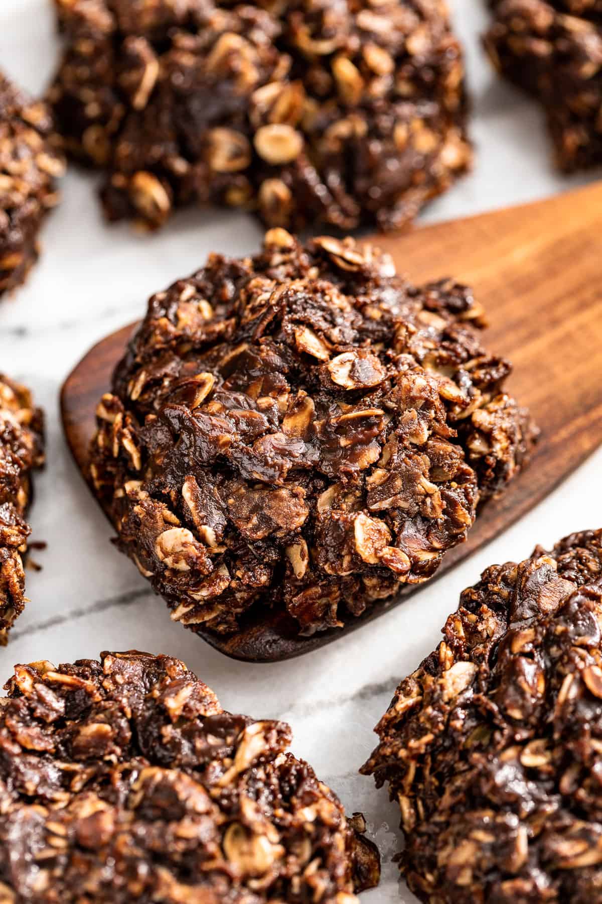 Side view of Healthy No Bake Cookies with a wood spatula scooping one up.