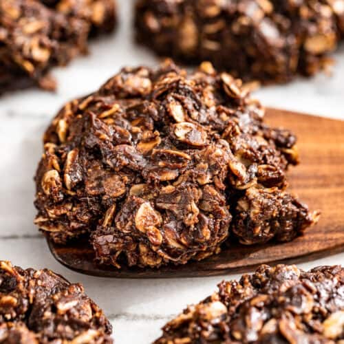 Side view of Healthy No Bake Cookies with a wood spatula scooping one up.