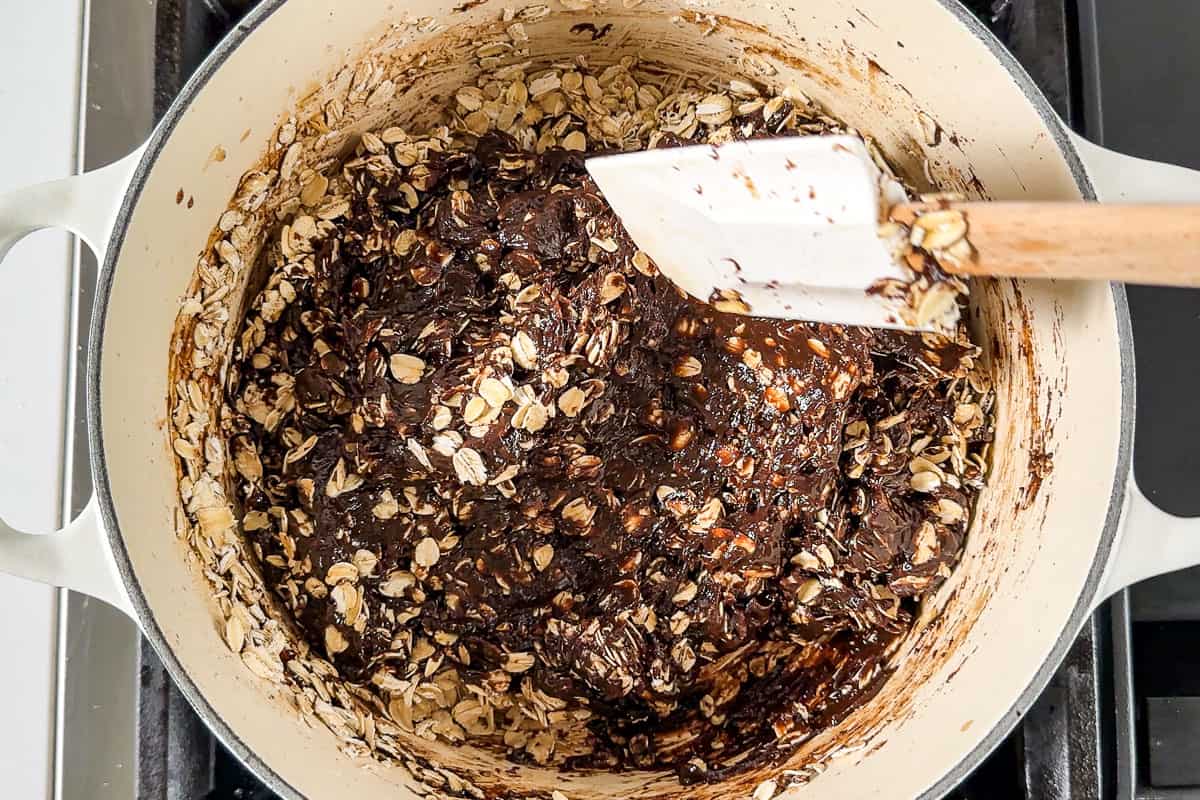 Adding the oats to the chocolate mixture in a large white pot.