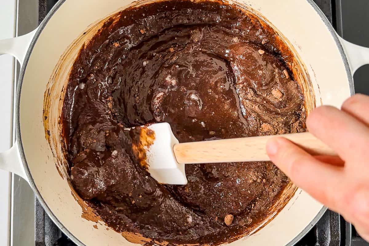 Mixing together the coconut sugar, cocoa powder, coconut oil, and milk together in a large white pot.