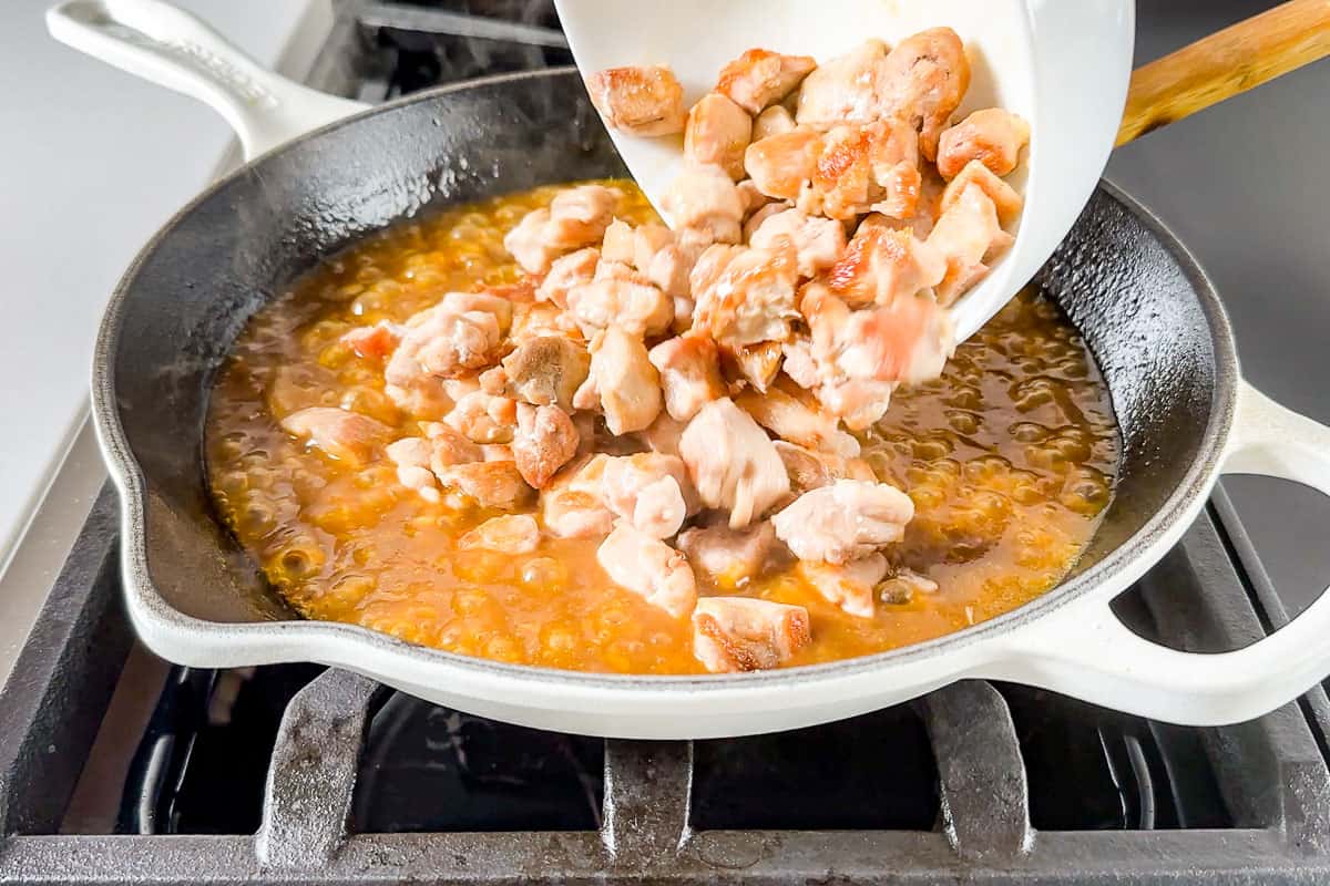 Adding the chicken back to the pan with the reduced orange sauce.