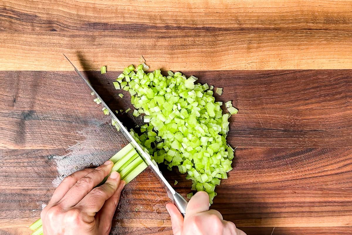 Mincing celery on a wood cutting board.