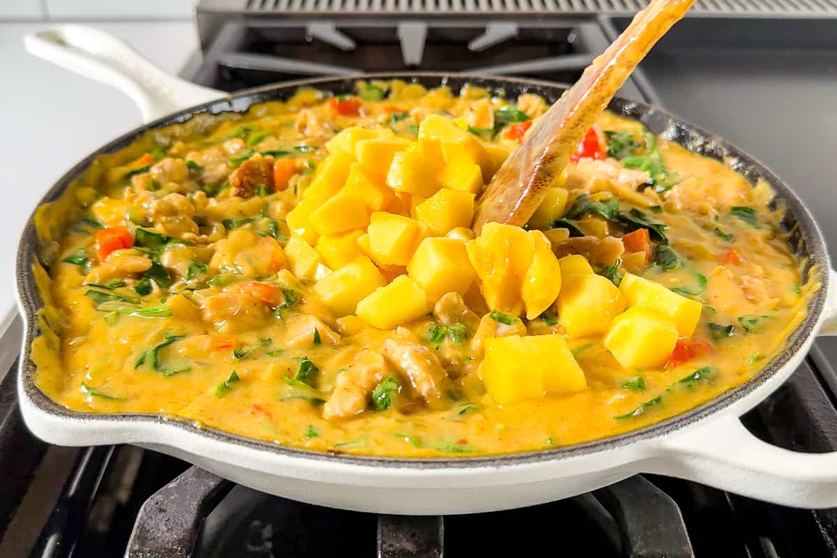Adding the mango chunks to the finished curry.