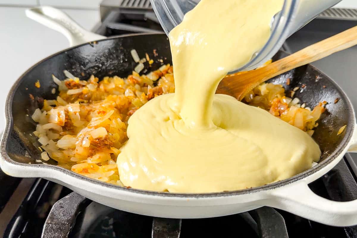 Adding the coconut mango sauce to the cooked onion mixture.