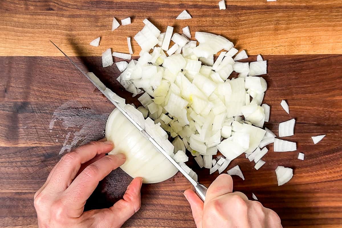 Dicing an onion on a wood cutting board.