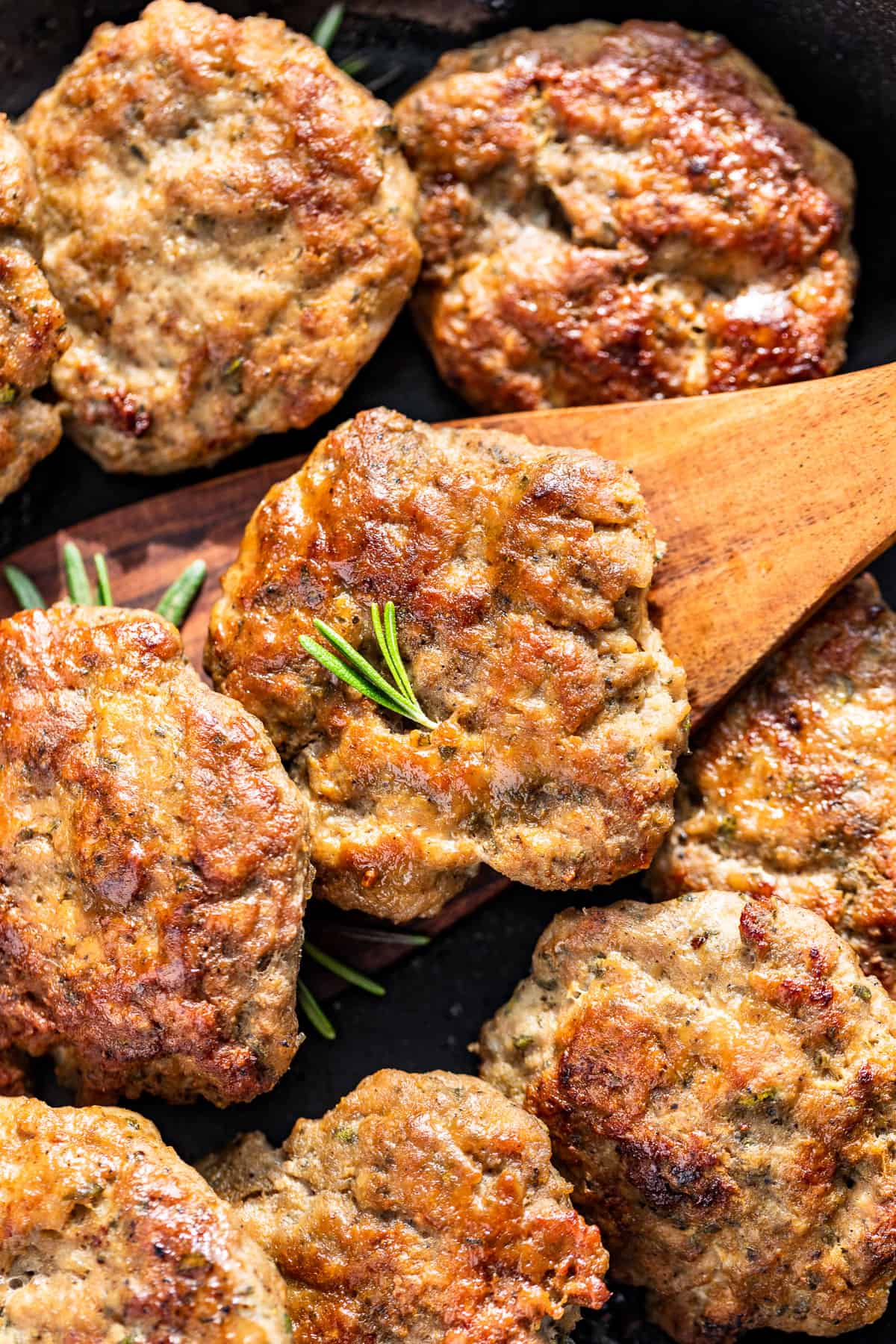 Close macro shot of Turkey Breakfast Sausage patties with a wood spatula lifting one out.