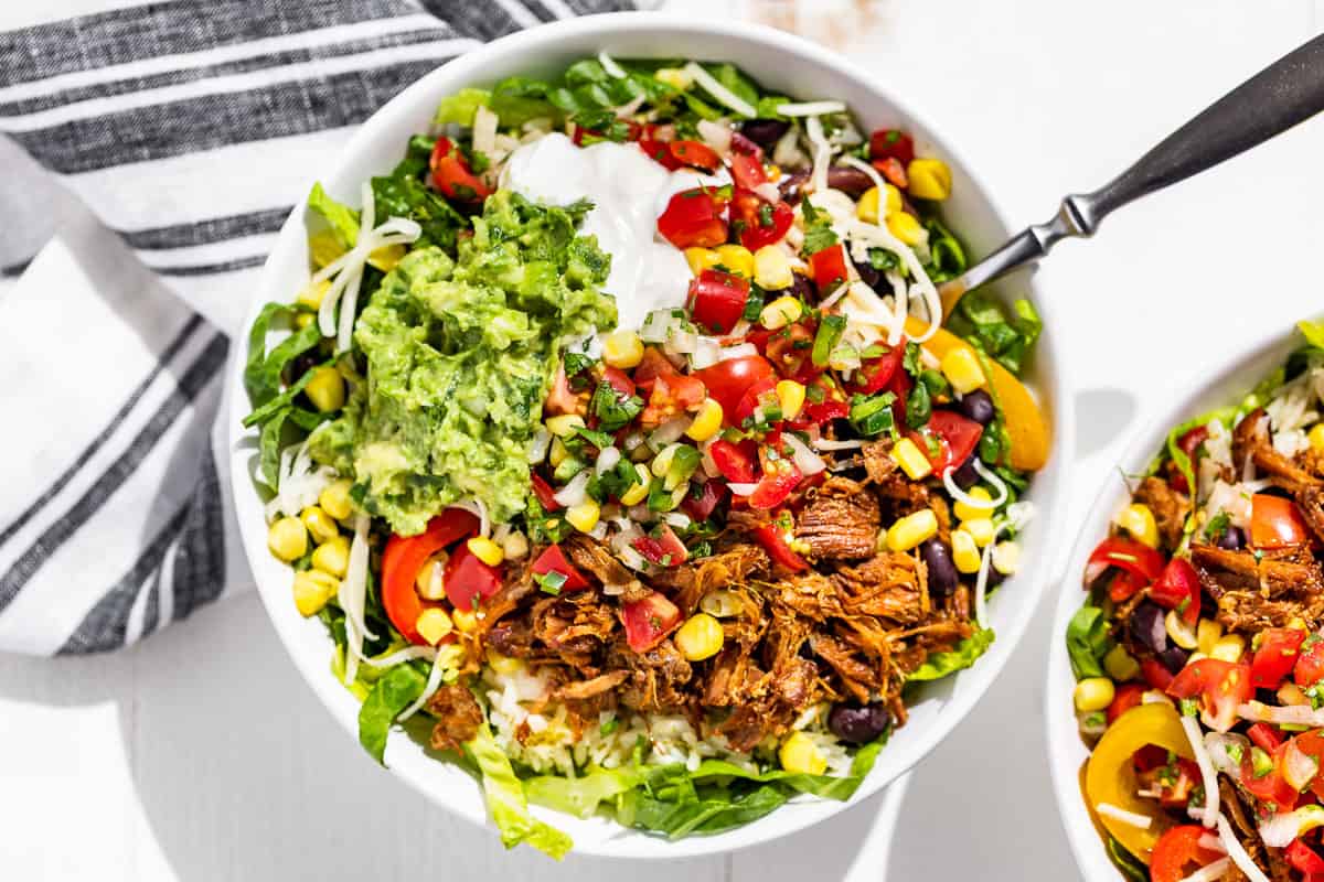Straight down view of 2 Carnitas Burrito Bowls with a fork in one.