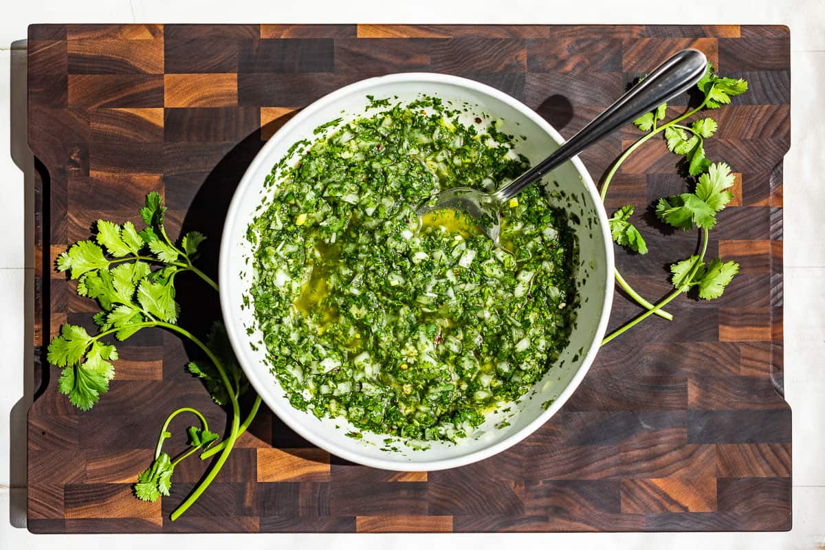 Stirring together the cilantro chimichurri on a wood cutting board.