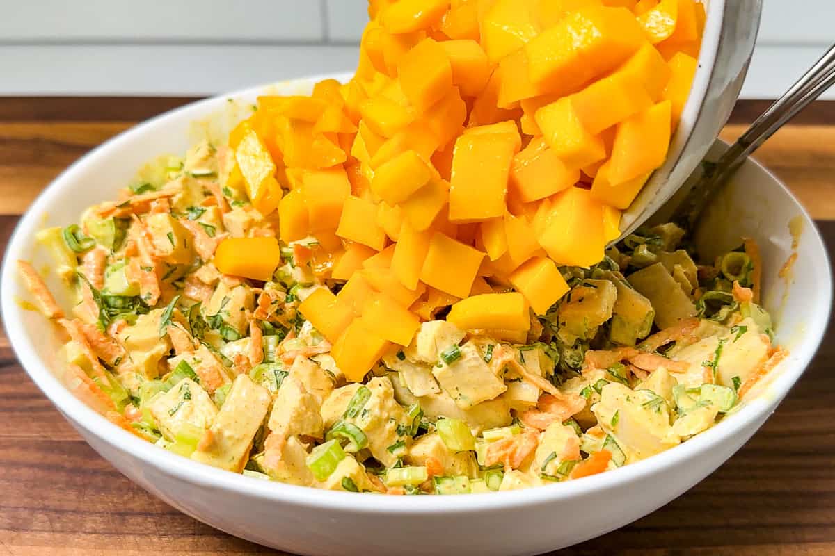 Adding fresh cubed mango to the curried chicken salad.