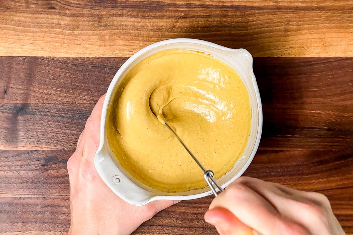 Whisking together the curried mayo dressing in a small pottery bowl.