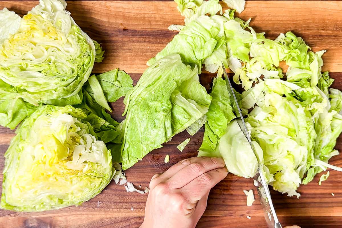 Chopped the iceberg lettuce on a wood cutting board with a large chef's knife.