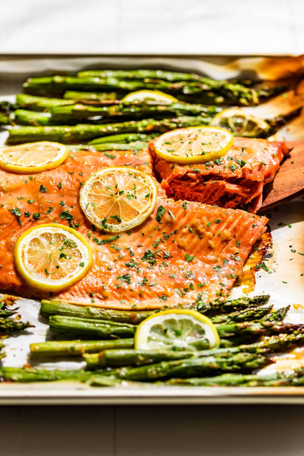 A side view of the Honey Dijon Salmon and Asparagus on a sheet pan with lemon slices.