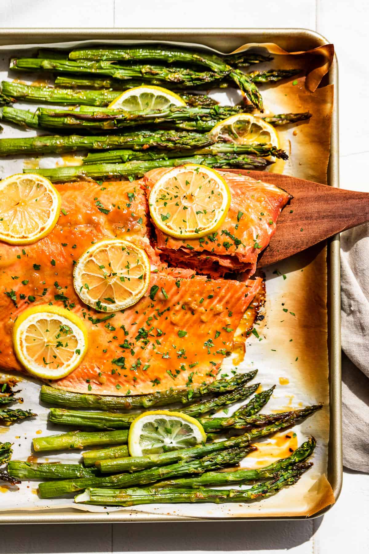 A straight down view of Honey Dijon Salmon and Asparagus with a piece of salmon being lifted out.