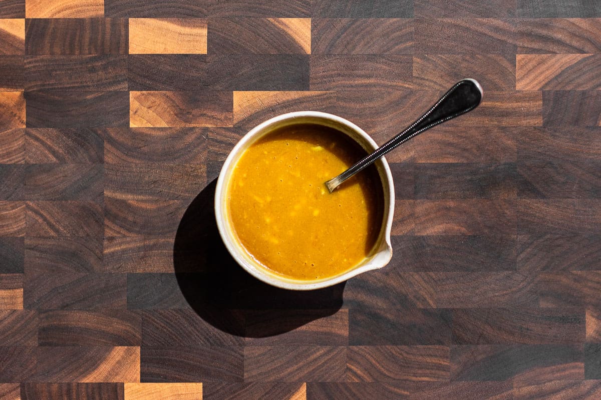 Mixing together the honey mustard sauce in a small bowl placed on a wood cutting board.