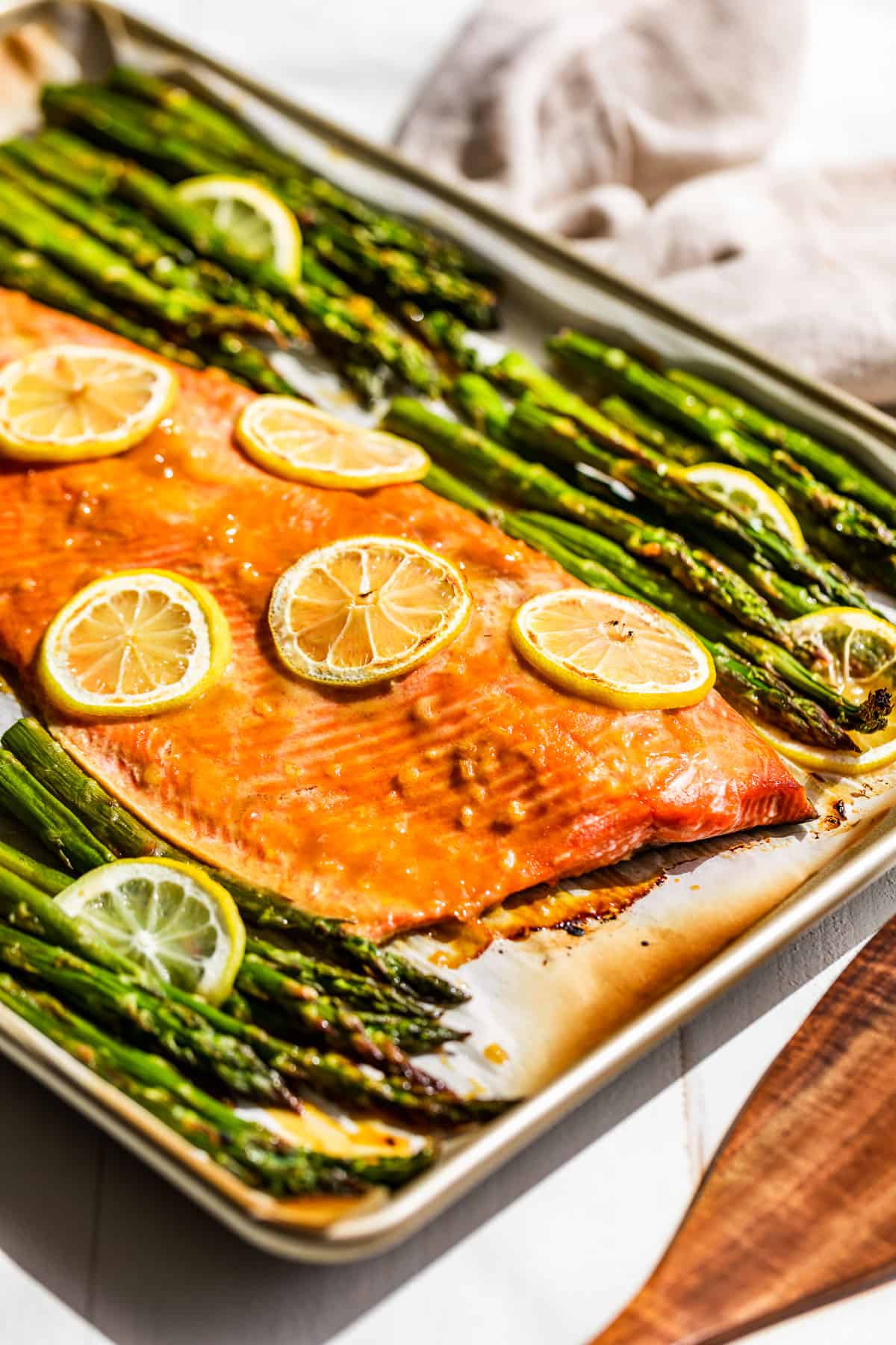 Side view of Sheet Pan Salmon and Asparagus with a wood spatula on the side.