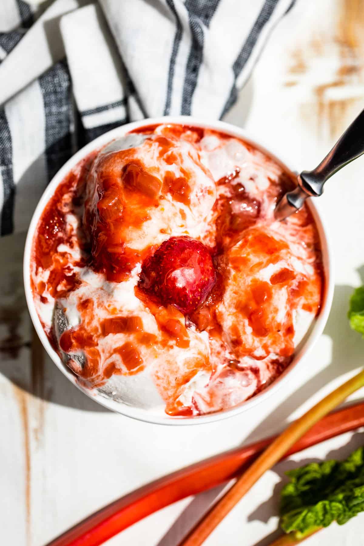 A straight down view of Strawberry Rhubarb Sauce over coconut ice cream in a white bowl.