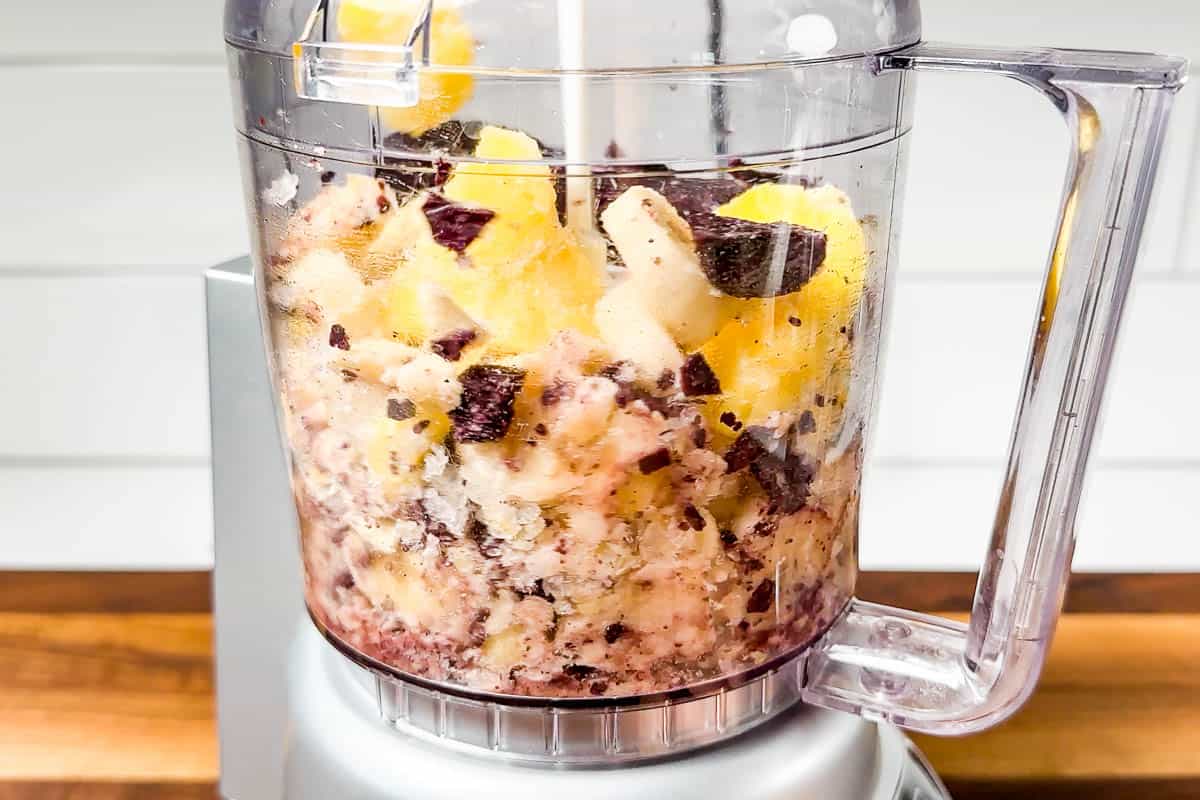 Blending the frozen acai, bananas, and pineapple in a small food processor.