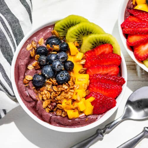 Straight down view of two Acai bowls topped with fruit and granola.