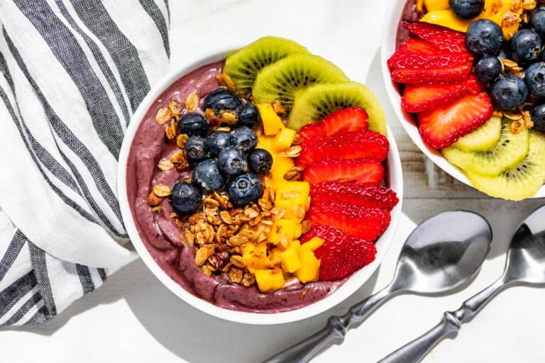 Straight down view of two Acai bowls topped with fruit and granola.