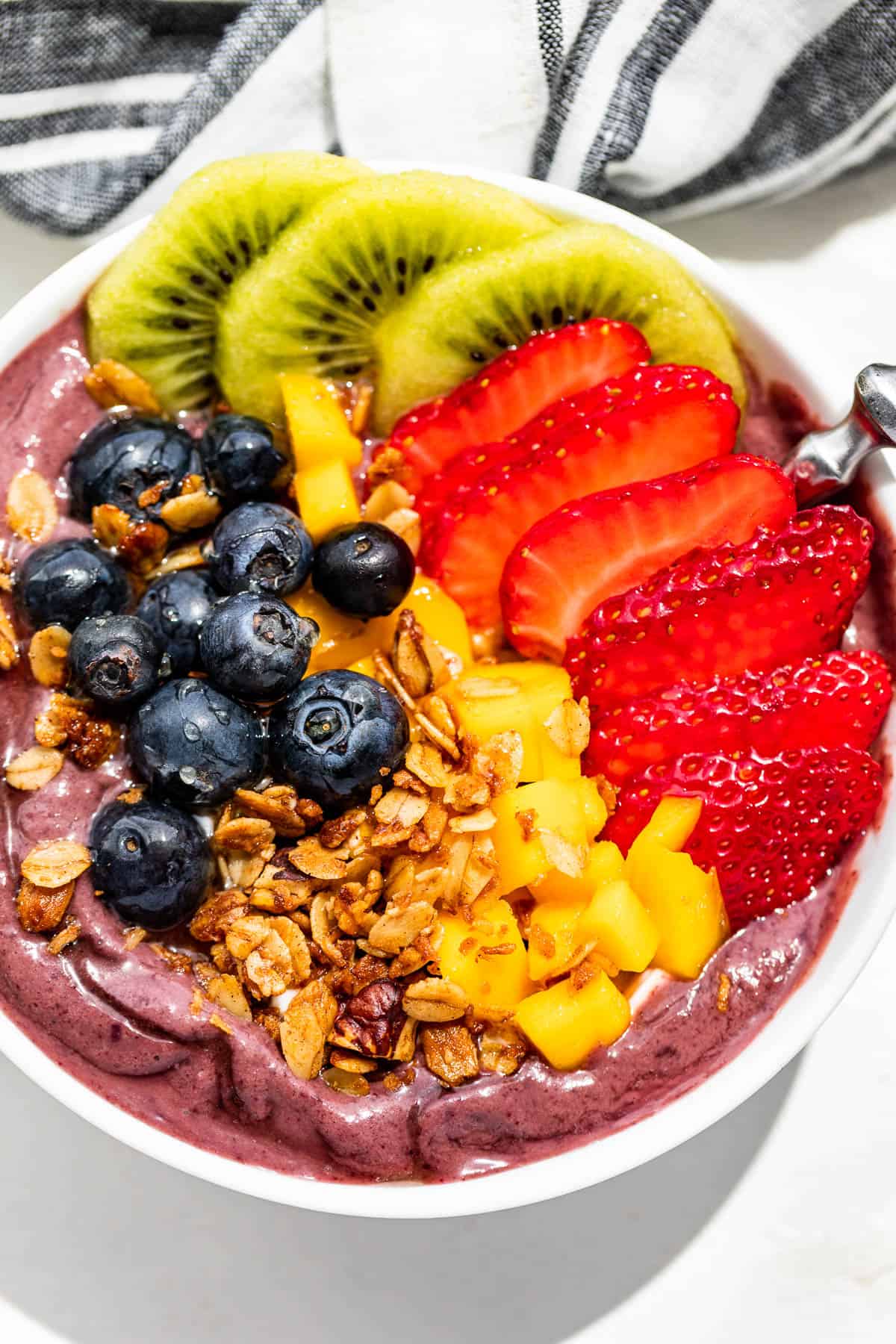Straight down close up view of a Acai Bowl topped with fresh fruit and granola.