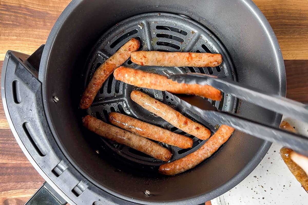 Turning the breakfast sausage links in the air fryer basket halfway through the cooking time.