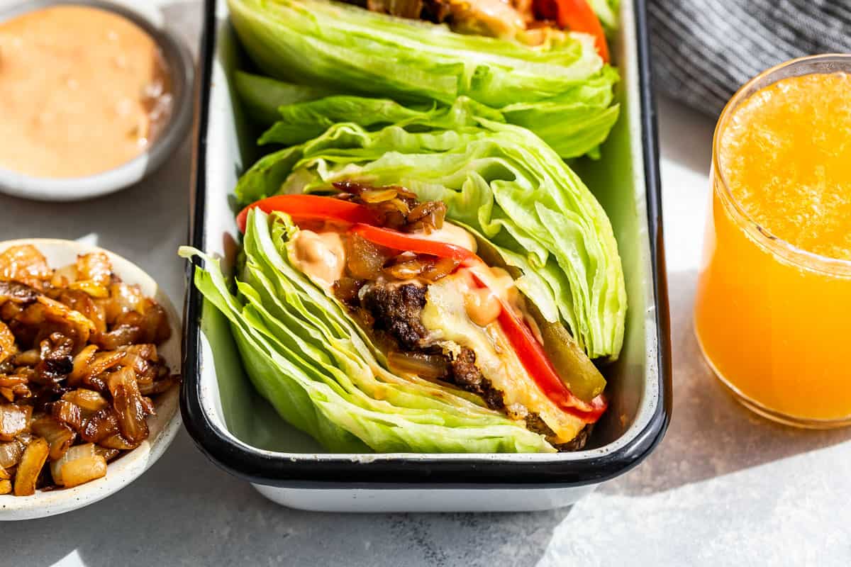 Burger Lettuce Wraps in a rectangular container with burger sauce and caramelized onions on the side.