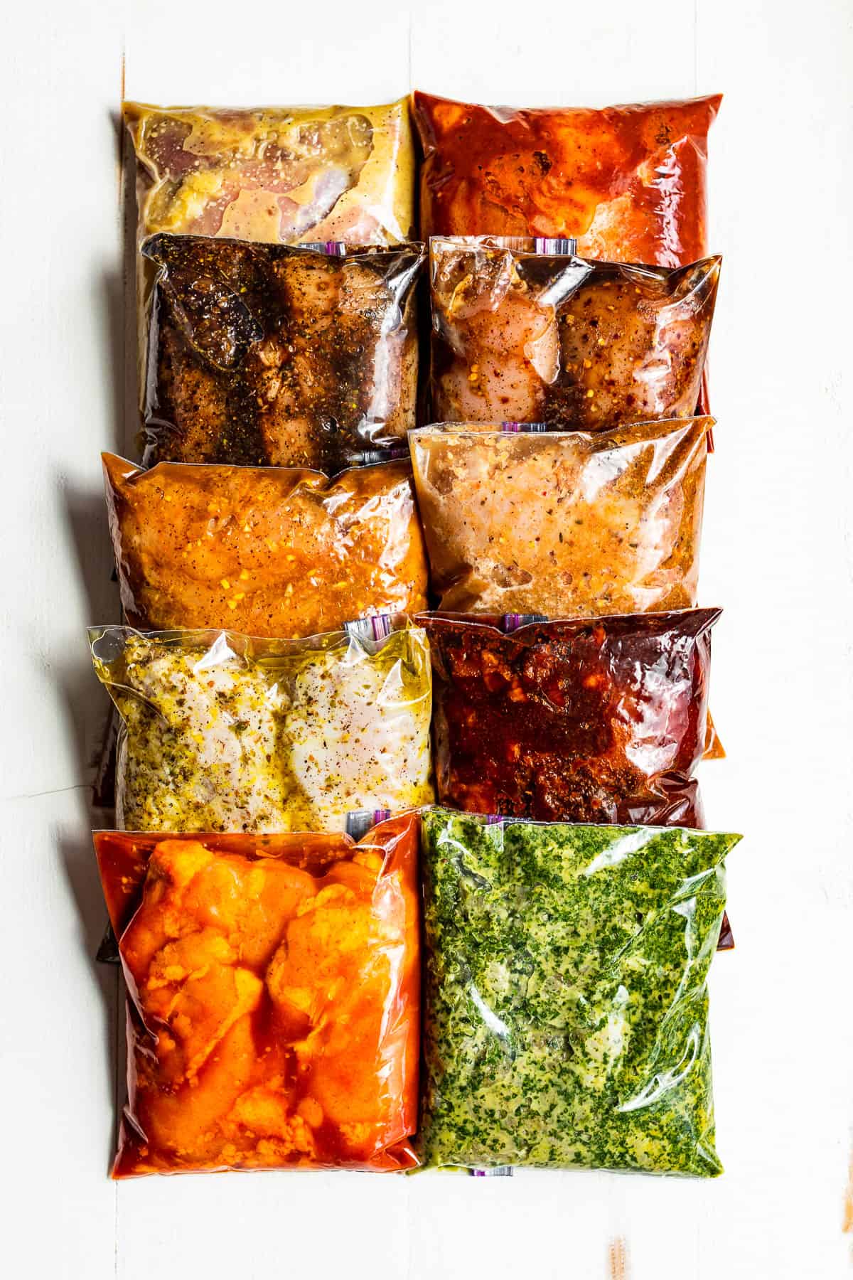 Ten different chicken marinades in bags on a white background.