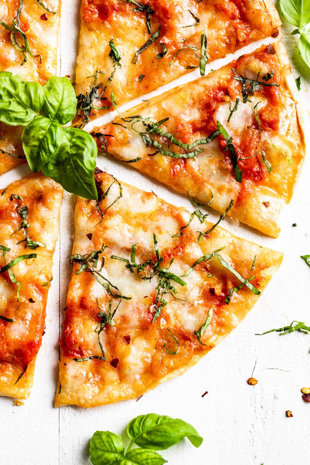 A grilled tortilla pizza cut into wedges on a white background.