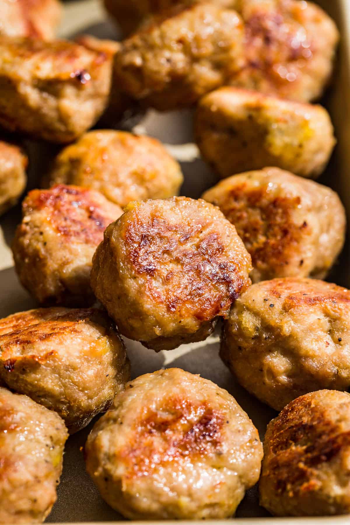 Close macro view of Baked Turkey Meatballs on a gold baking sheet.