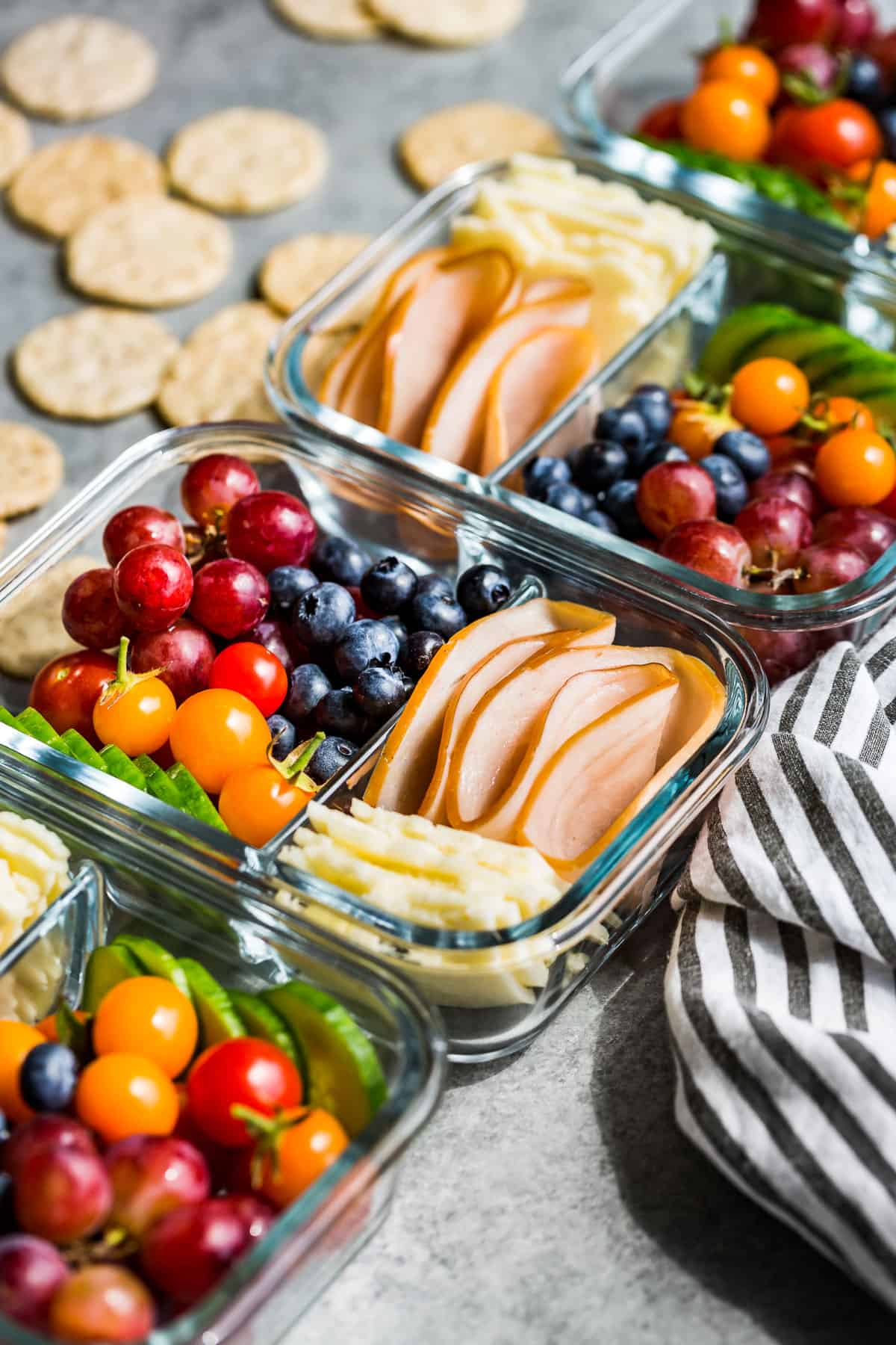 Side view of Adult Lunchables in meal prep glass containers with crackers in the background.