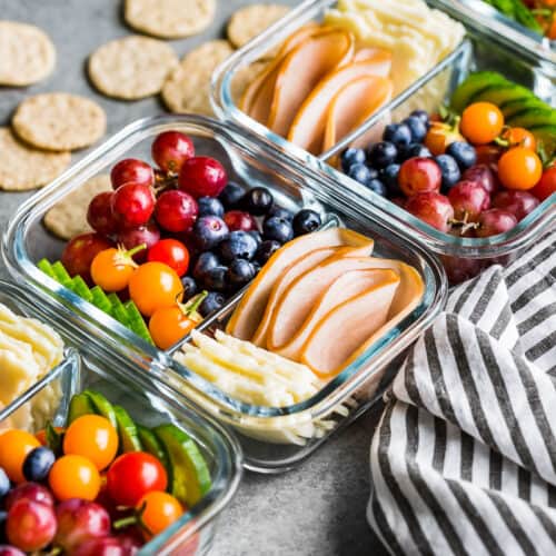 Side view of four containers of adult lunchables with crackers on the side.