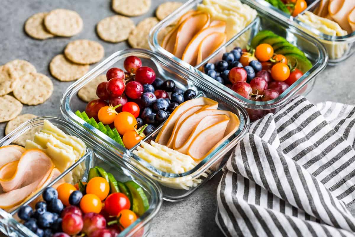 Side view of four containers of adult lunchables with crackers on the side.