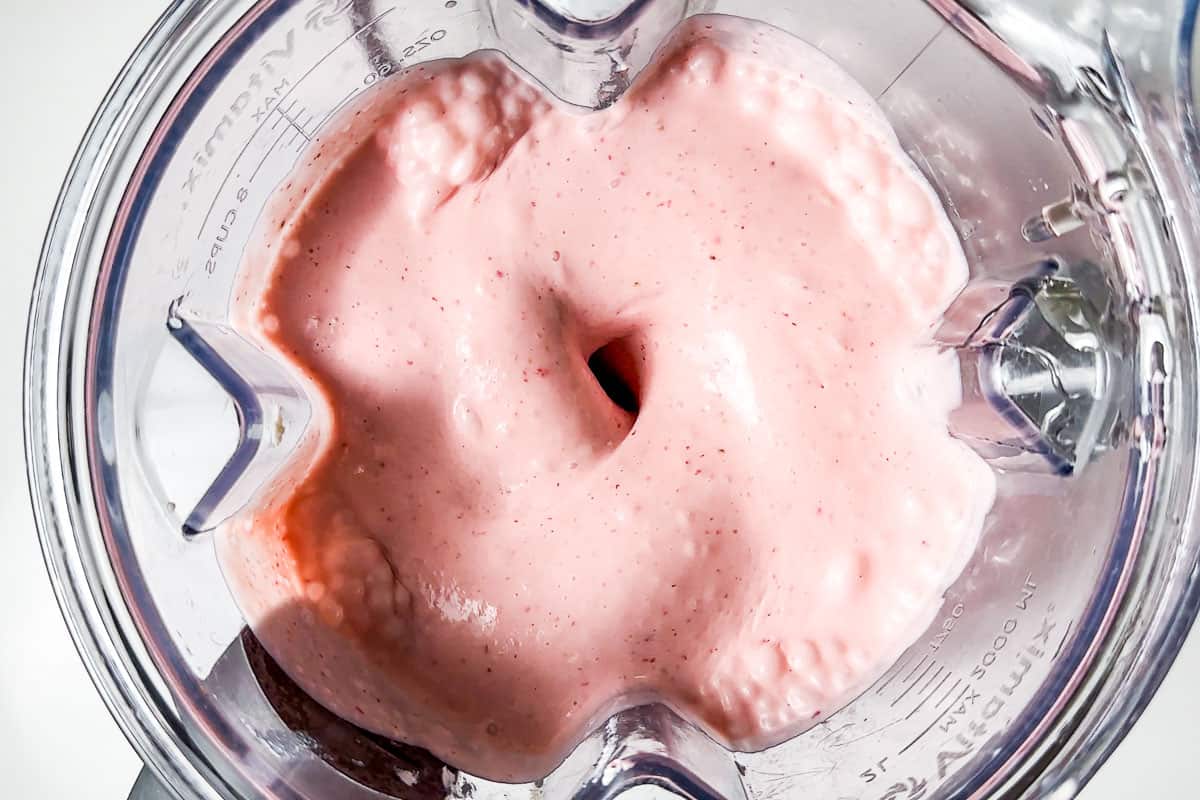 Blending the strawberries into the cream cheese cream mixture in a blender container.