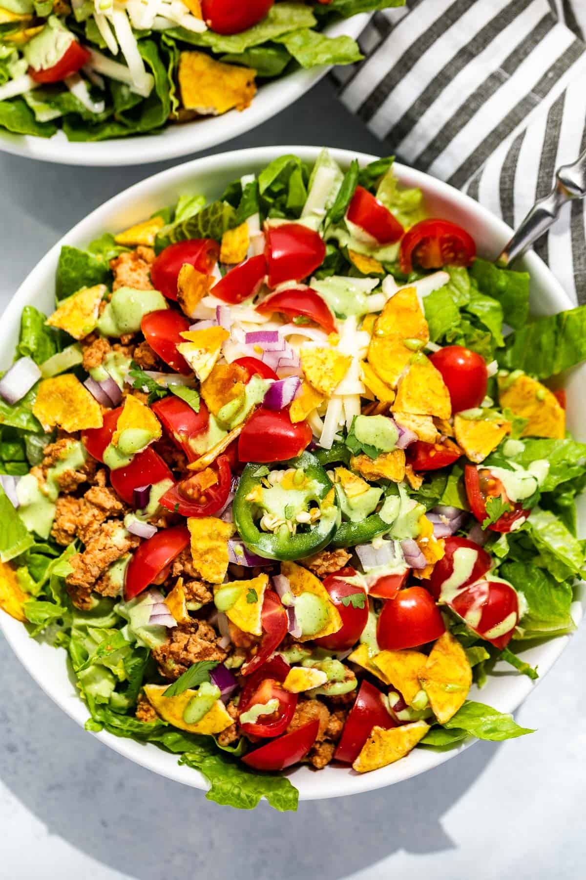 Straight down close view of Turkey Taco Salad in a white bowl with a black and white striped linen.