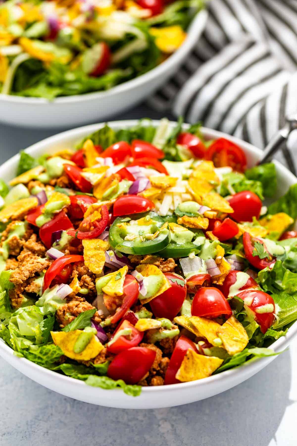 Side close up view of Turkey Taco Salad in a white bowl topped with cilantro dressing.