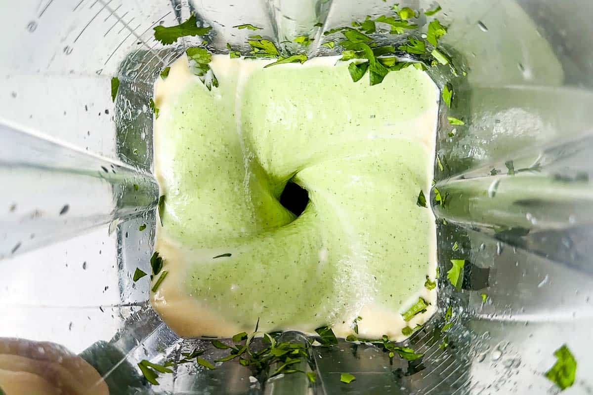 Blending the cilantro dressing in a blender container.