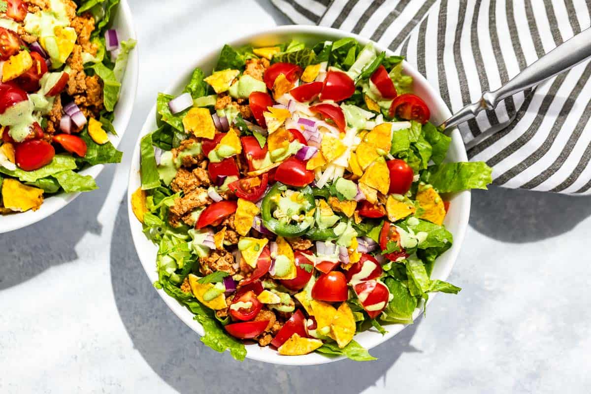 Straight down view of two bowls of turkey taco salad on a blue background.