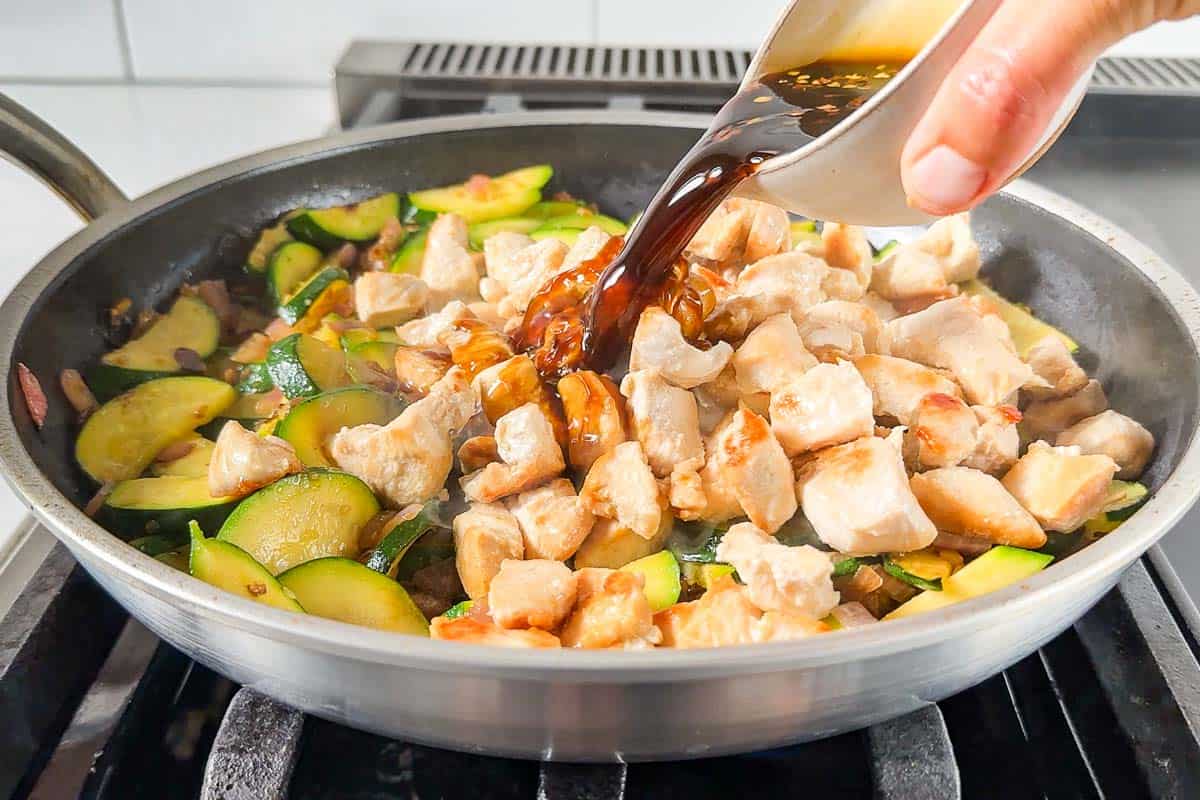 Adding the chicken and sauce to the skillet with the zucchini onion mixture.