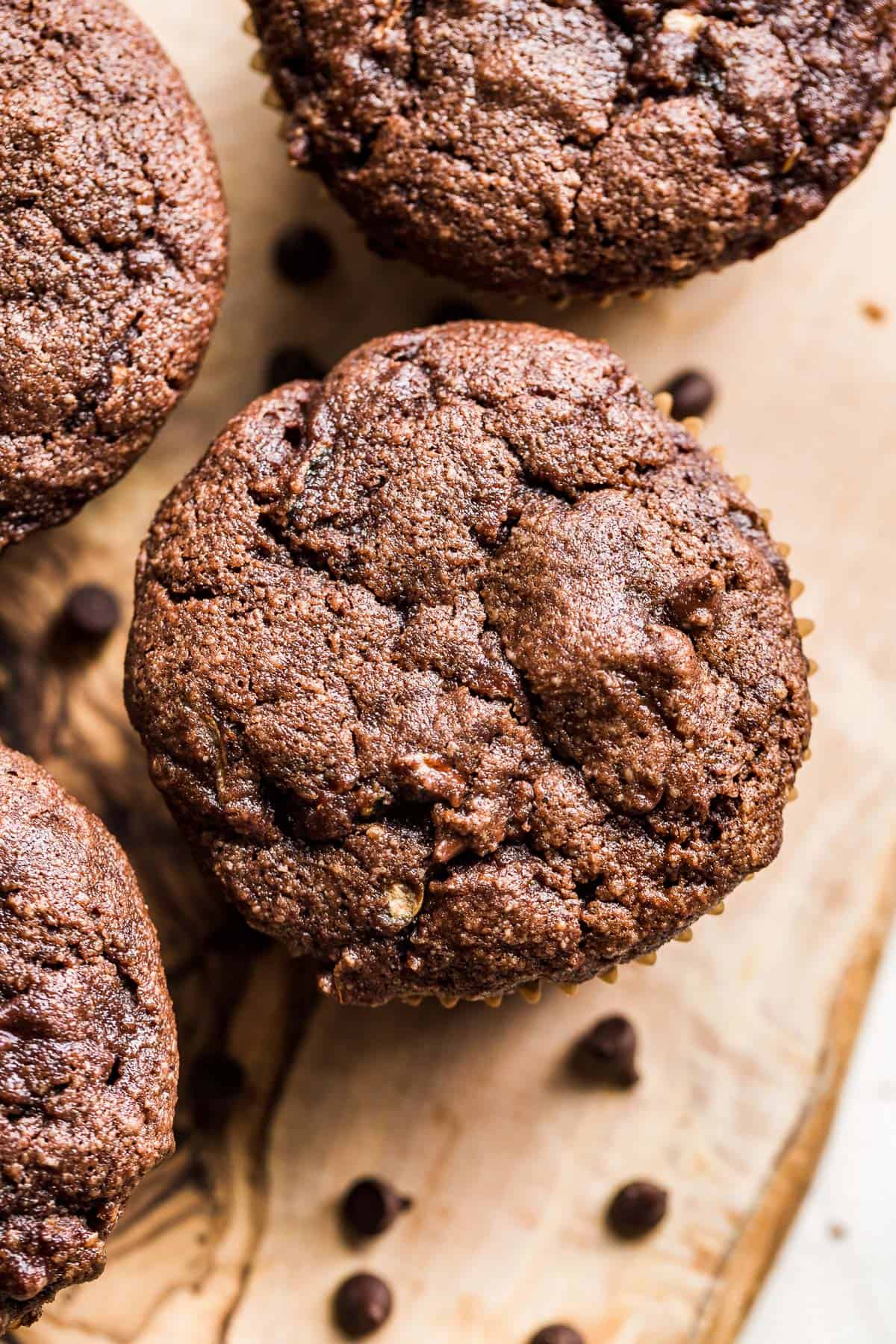 Close up straight down view of paleo chocolate zucchini muffins on a wood cutting board.