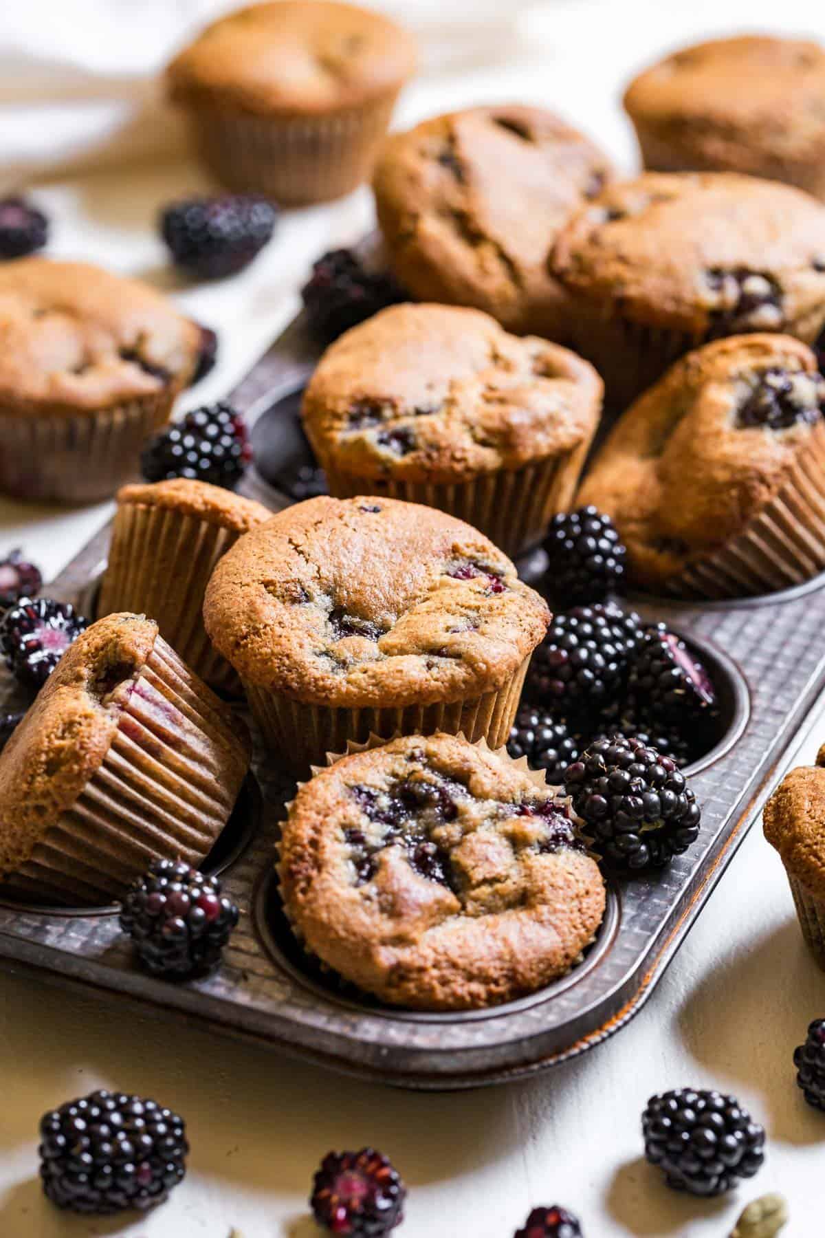 Side view of almond flour blackberry muffins in an antique muffin tin.