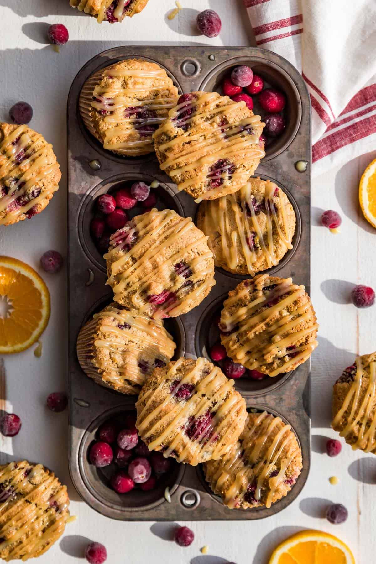 Paleo Cranberry Orange Muffins sitting in an antique muffin tin with cranberries around it.