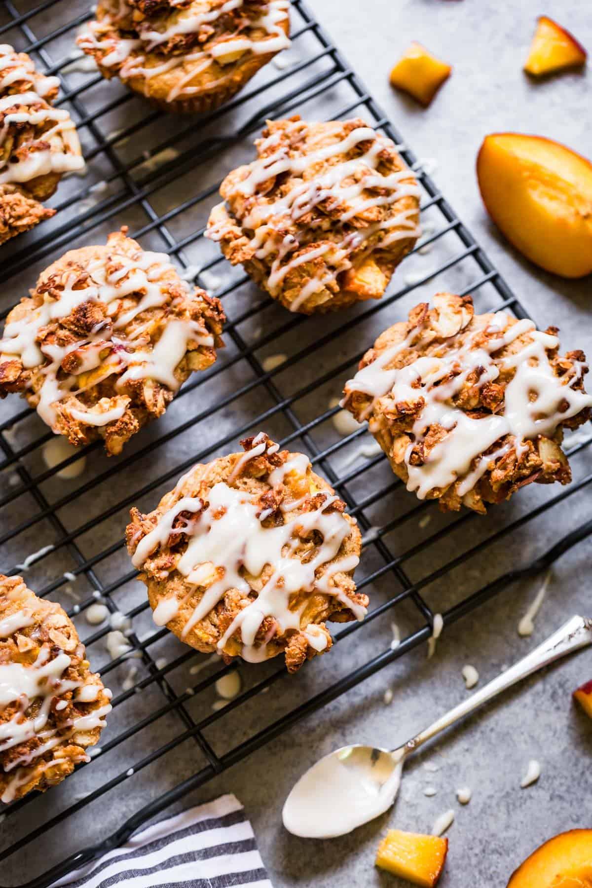 Straight down view of almond flour peach muffins being glazed on a cooling rack.