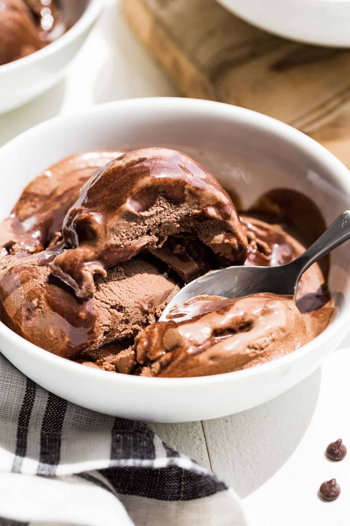 Close up view of chocolate avocado ice cream in a white bowl with a bite scooped out.