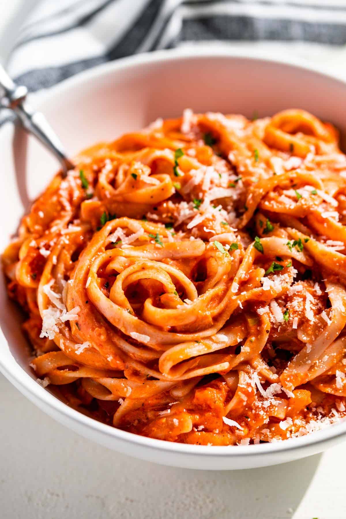 Side view of Creamy Tomato Pasta in a white bowl with a fork in the side of the pasta bowl.