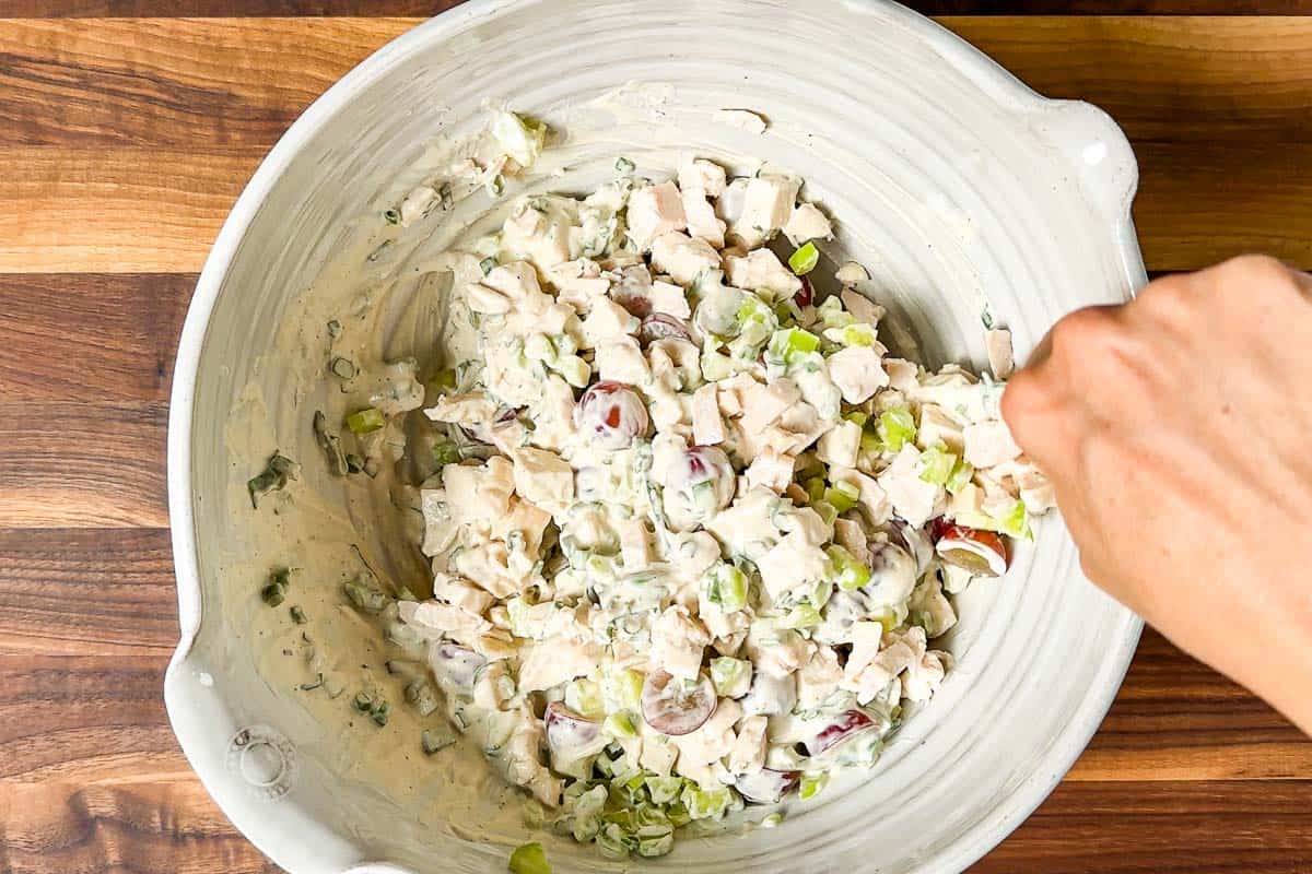 Stirring together the Healthy Chicken Salad and seasoning to taste with salt and pepper.