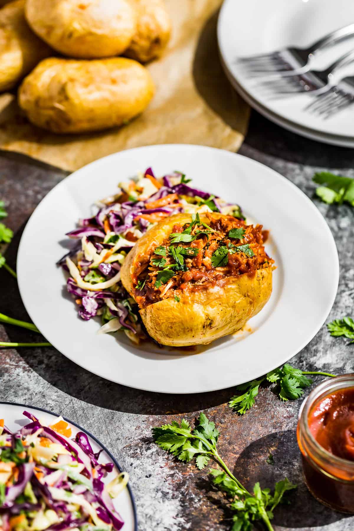 Side view of Instant Pot BBQ Chicken stuffed into a baked potato with slaw on the side.