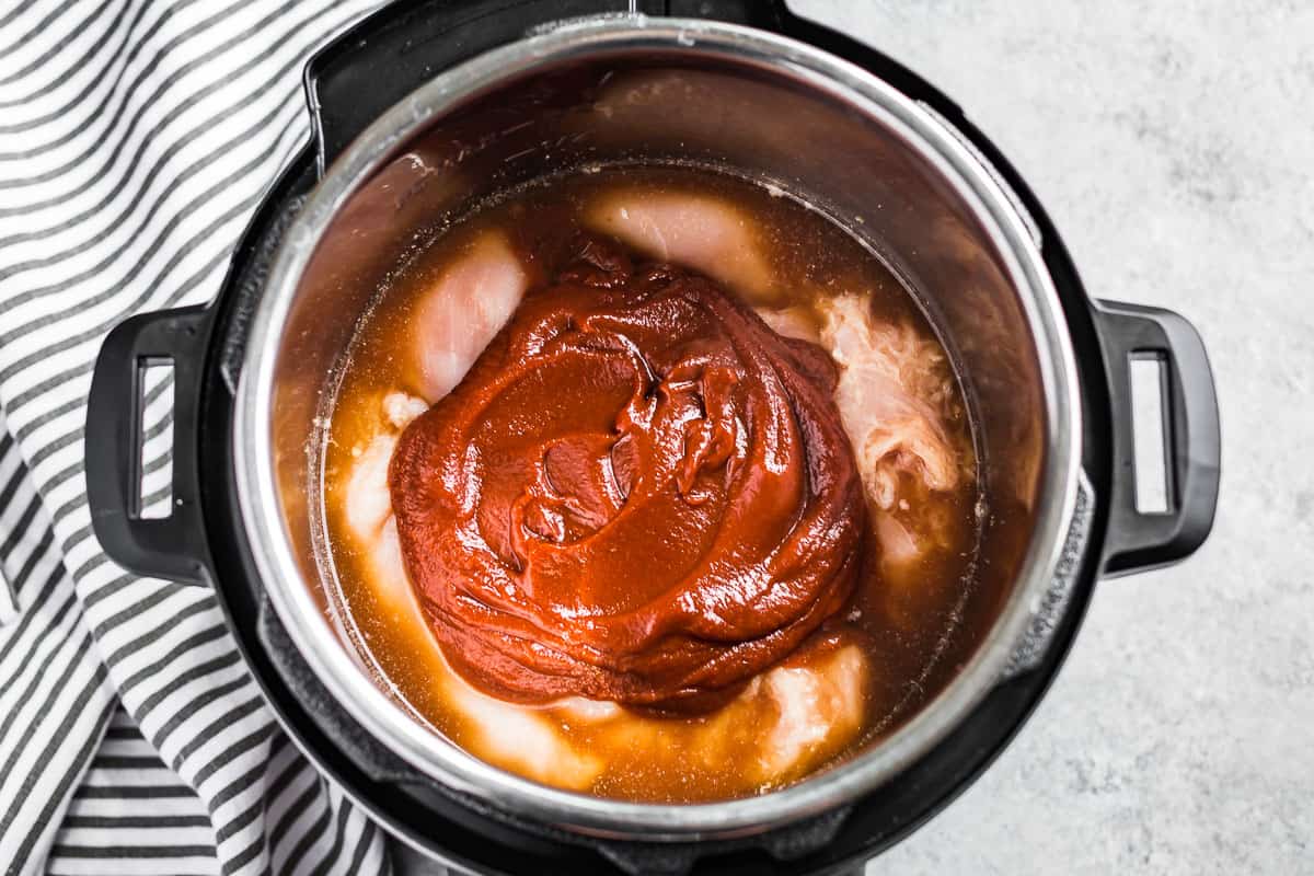 Topping the chicken breasts with the bbq sauce in an instant pot.