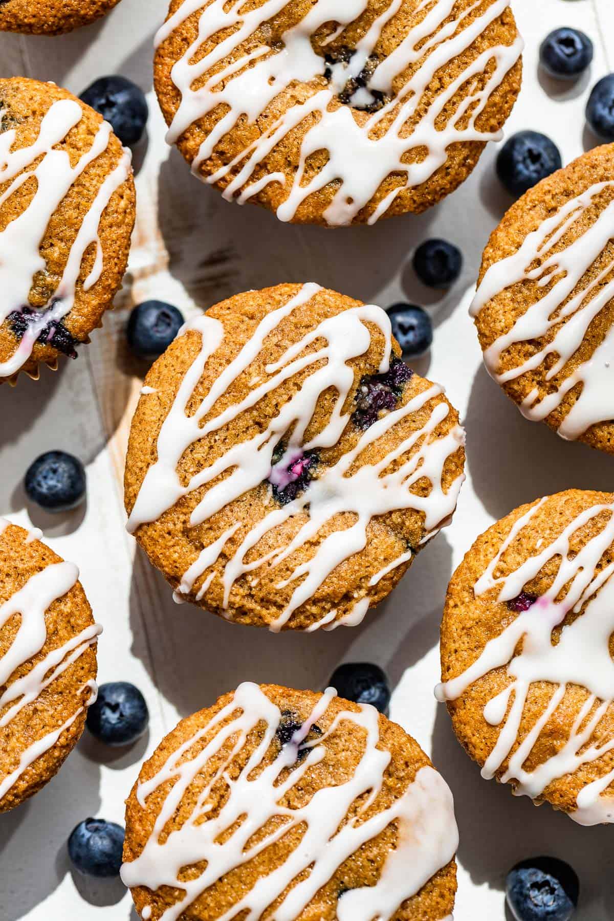 Looking straight down at glazed almond flour blueberry muffins on a white background.