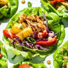 Side view of Thai Lettuce Wraps on a blue background drizzled with peanut sauce.